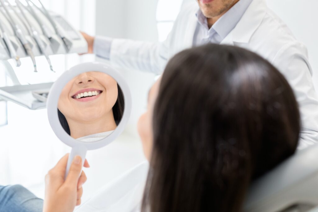 Happy female patient looking at mirror in dental clinic